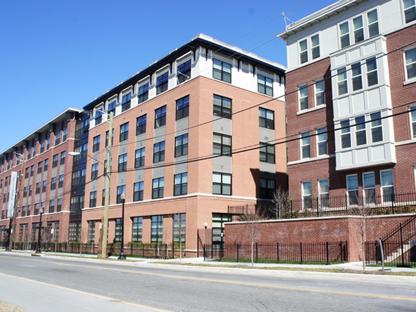 Multi-story, multifamily residential buildings with brick exteriors line a street.