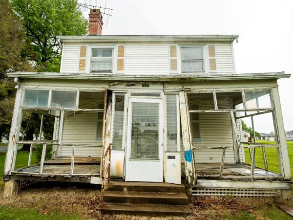 Photograph of a house with a large front porch that had fallen into disrepair.
