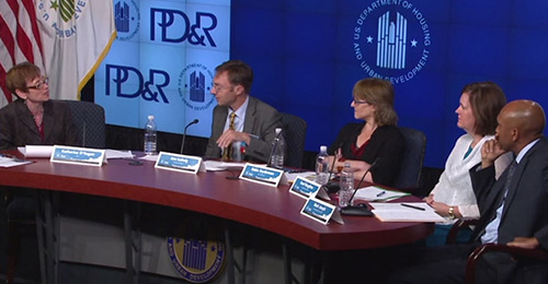 Photograph of Assistant Secretary for Policy Development and Research Katherine O’Regan and four panelists at a table on stage in front of banners displaying the HUD and PD&R logos.